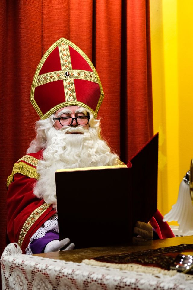 Sinterklaas leest in zijn grote boek in het pakjeshuis in Putten