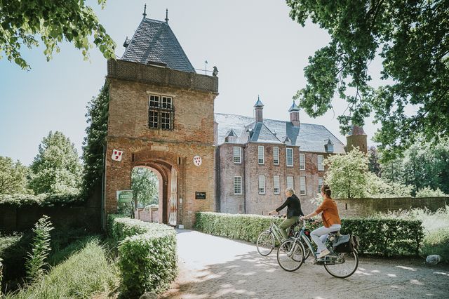 Twee vriendinnen fietsen door de poort van Slot Zuylen