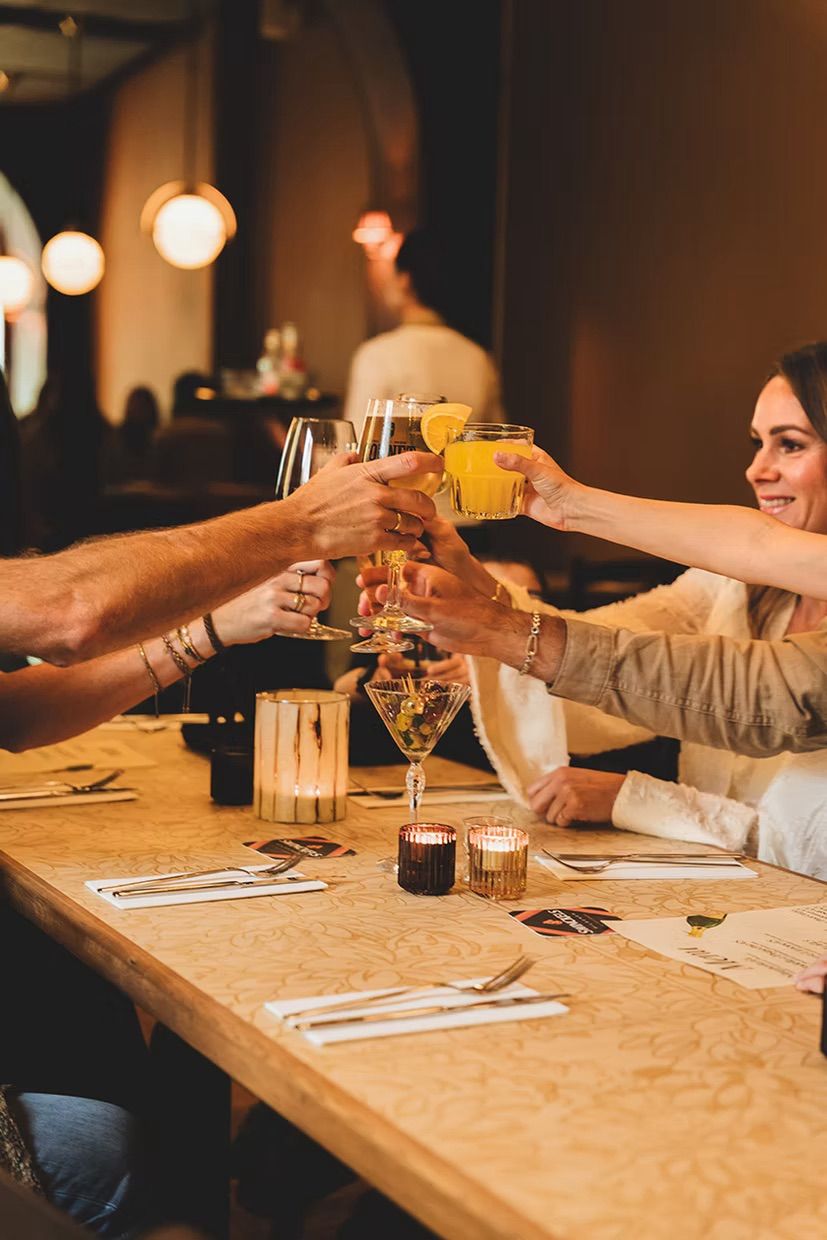 Mensen die proosten met verschillende soorten drankjes bij Allora