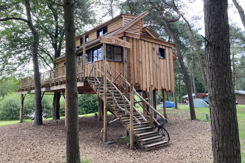 Een grote boomhut die op een camping staat.