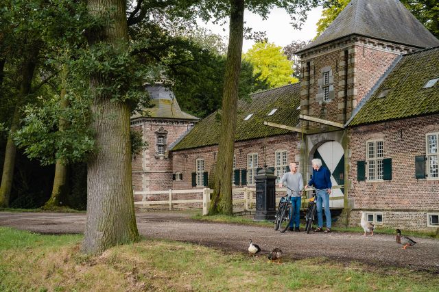 Anton en Kees met de fiets aan de hand voor de zijpoort van Kasteel Gemert.