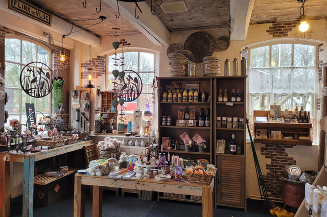 Een winkel waarin streekproducten en cadeau artikelen uitgestald staan in kasten en op tafels.