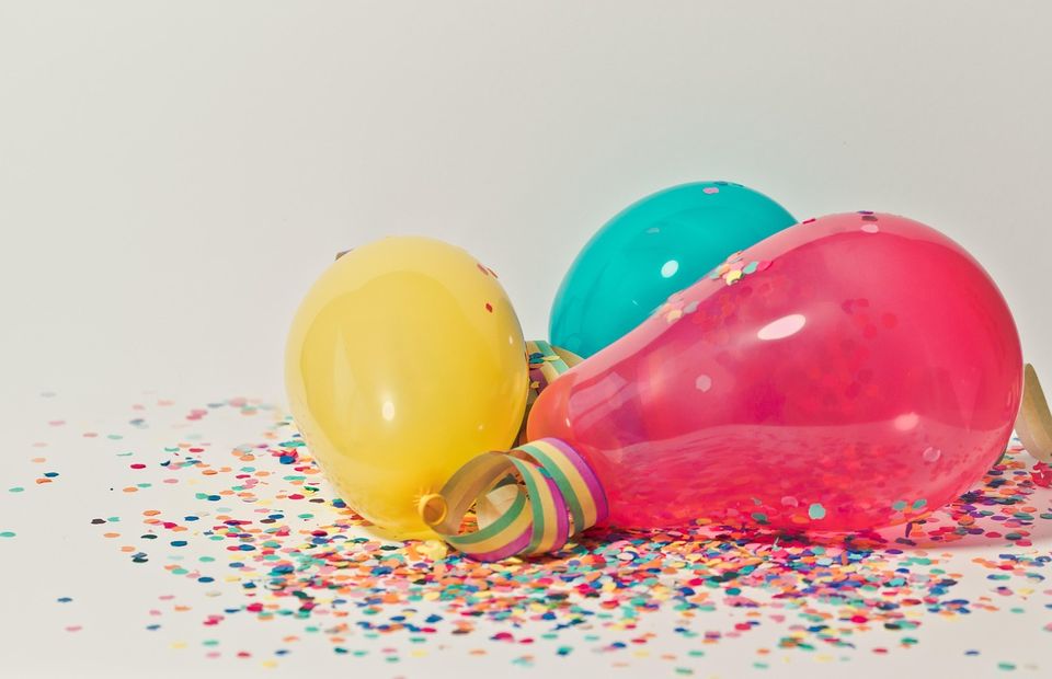 De afbeelding toont gekleurde ballonnen en confetti als sfeerbeeld, zonder tekst of inhoudelijke boodschap. Volgens WCAG mag deze door schermlezers worden genegeerd.