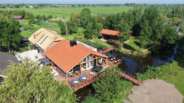 Restaurant De Oortjeshoeve in Kamerik, Groene Hart. Luchtfoto van restaurant met terras aan het water, rieten dak, houten veranda en uitzicht over het polderlandschap van het Groene Hart.