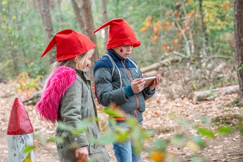 Twee kinderen lezen opdrachten van het kabouterbos. De kinderen hebben allebei een puntmuts op.