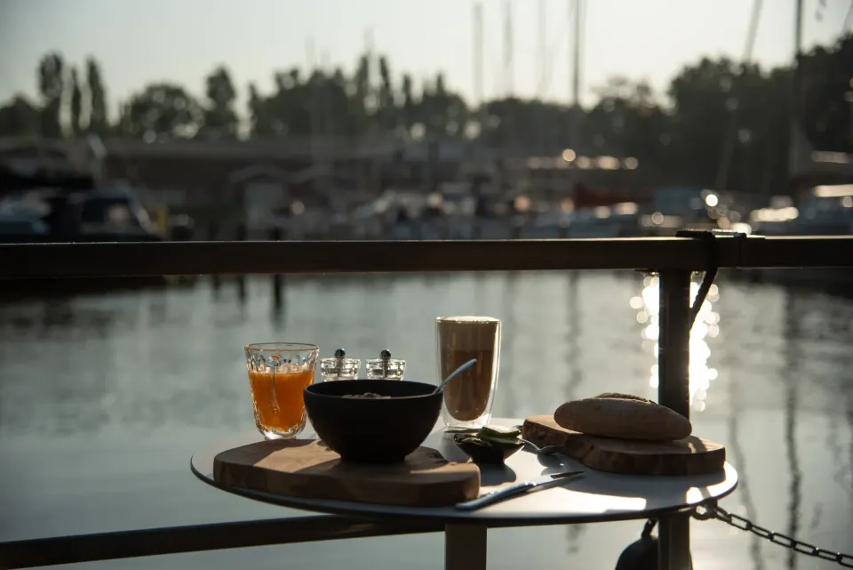 Een ontbijtje op een rond tafeltje op een Houseboat van Rent to Enjoy met uitzicht over het water.
