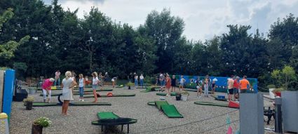 Midgetgolfbaan Boer Hans in Montfoort, Groene Hart, groepsactiviteit in de buitenlucht met mensen die samen midgetgolf spelen op een speels aangelegd terrein tussen groen en bomen.