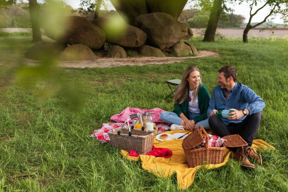 Vor dem Hünengrab sitzt ein Paar und macht ein Picknick.