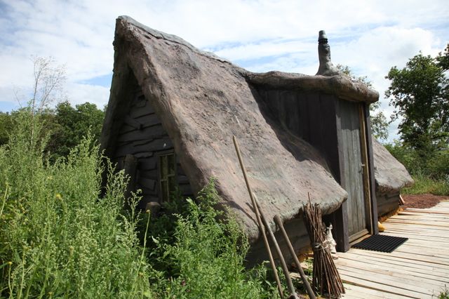 Een Drentse plaggenhut omringd door groen.