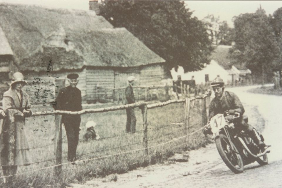 Historische foto van een motorcoureur die door Hooghalen rijdt tijdens de TT.