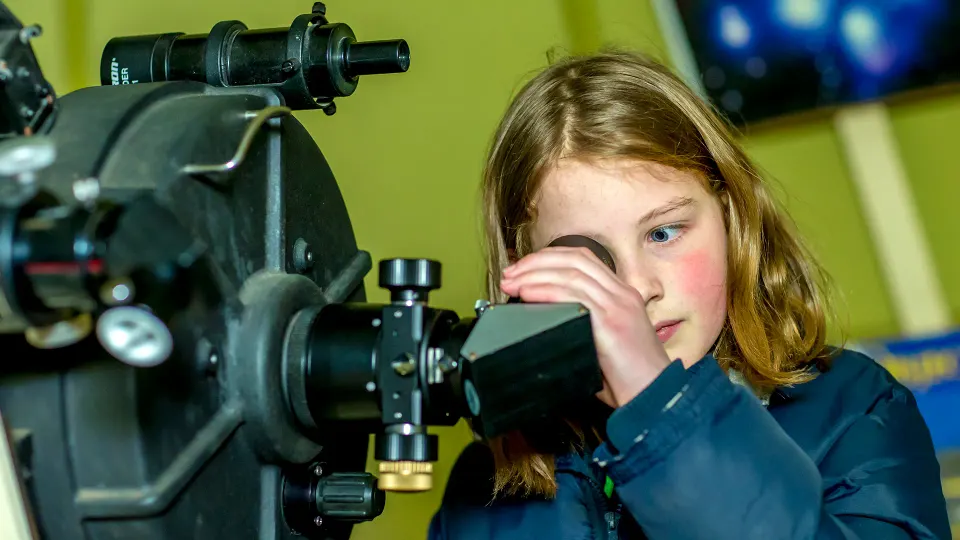 een meisje kijkt door een sterrenkijker