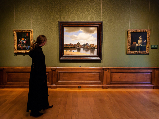 Bezoeker in het Mauritshuis kijkt naar het beroemde schilderij ​​Gezicht op Delft van Johannes Vermeer.