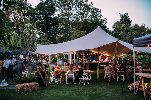 Het gezellige terras in de parktuin van Hotel Restaurant De Schildhoeve met tentdoekoverkapping en lichtjes.