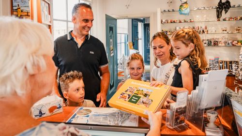 Een gezin die de kaasbelevingsbox aanneemt in de VVV van Edam