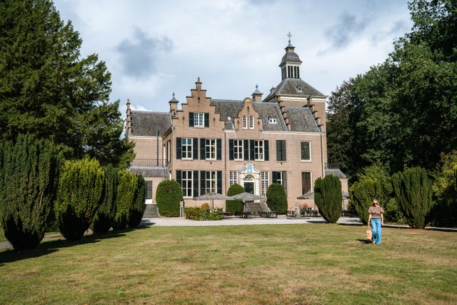 Vrouw loopt op gras voor Maarten Maartenshuis bij Landgoed Zonheuvel op De Utrechtse Heuvelrug