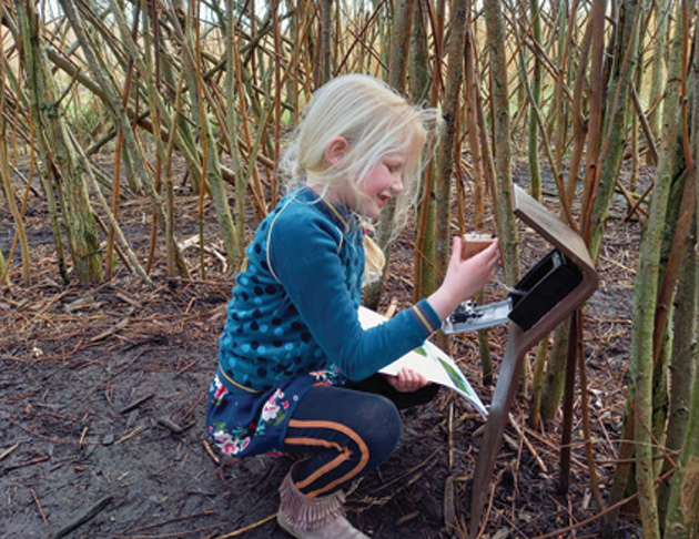 Meisje die de stempelspeurtocht aan het doen is, je ziet haar midden in de natuur zitten