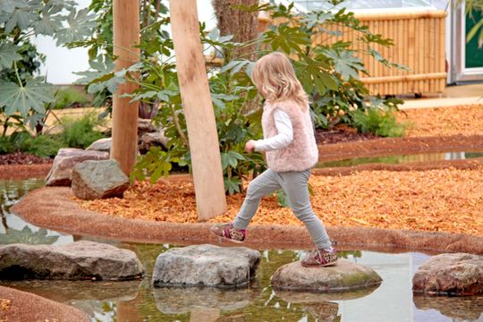 Een klein meisje loopt over stenen op het water in het jungle park van De Orchideeën Hoeve in Luttelgeest in de Noordoostpolder.