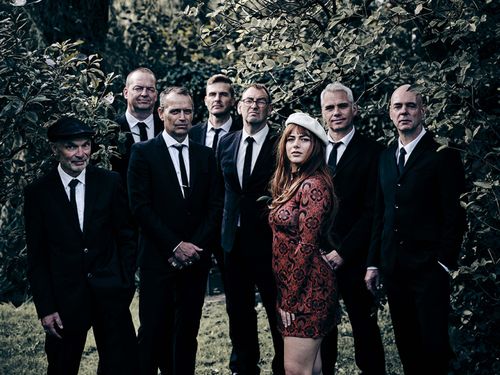 Een groep mannen in een pak met een vrouw erbij in een jurk