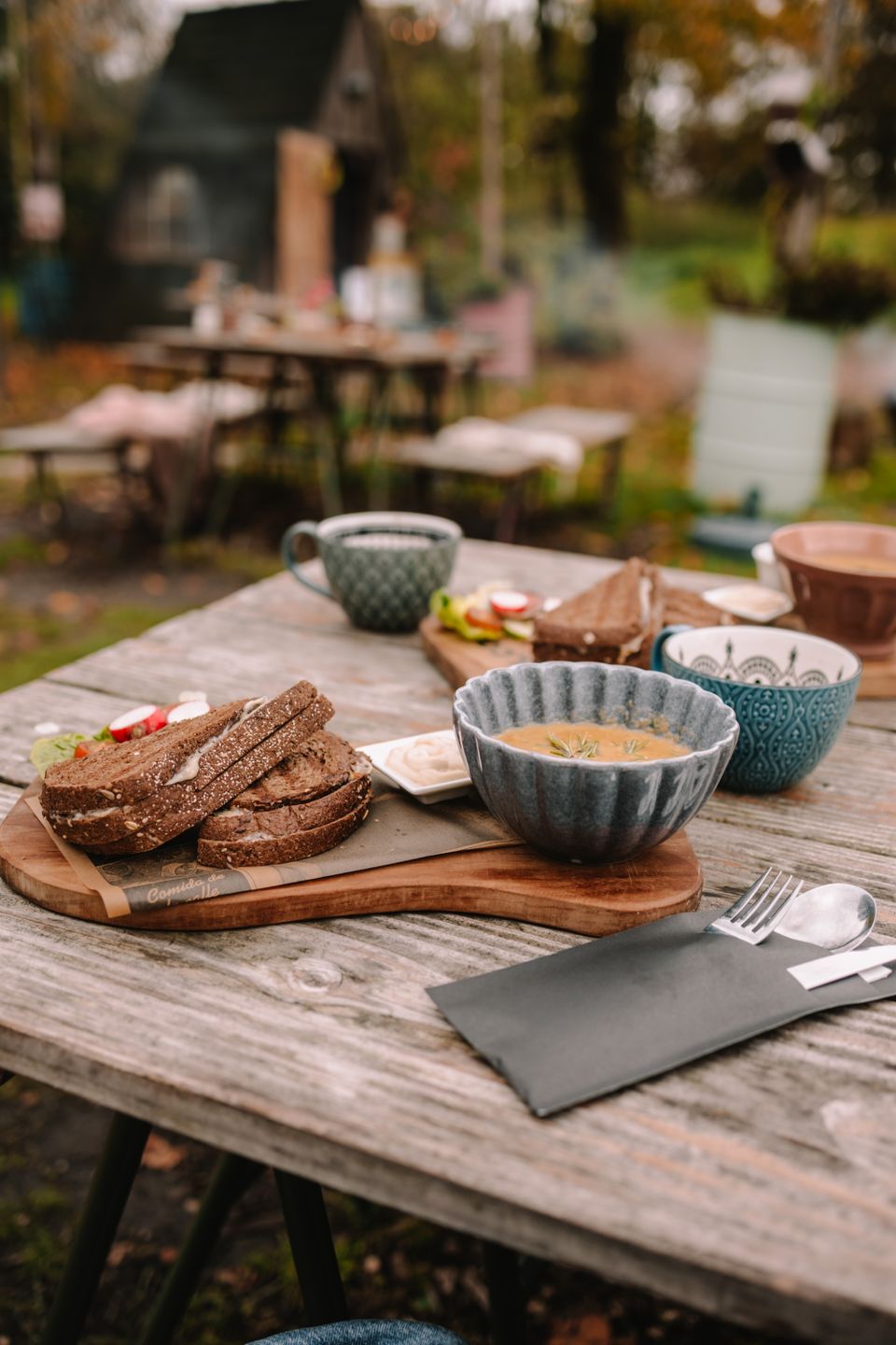 Lunch met broodjes, soep en warme dranken op een houten buitentafel bij Bij de Fortwachter.