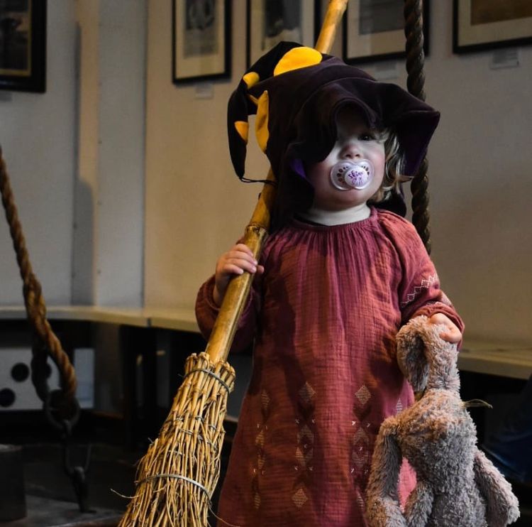 Klein kind met heksenmuts, bezemsteel en eigen knuffel vast
