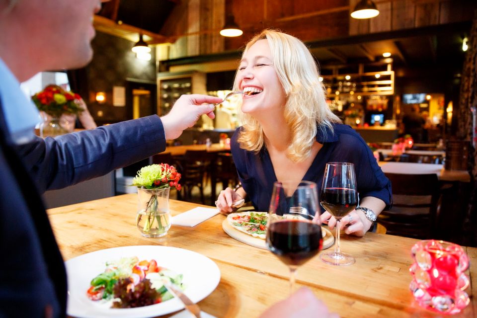 Man geeft vrouw een hapje eten tijdens het dineren.