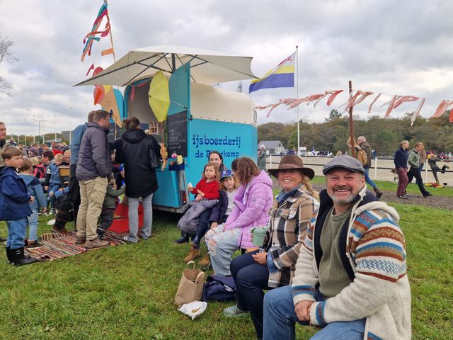 Verschillende lachende mensen op een evenement met onder andere een ijskraam.