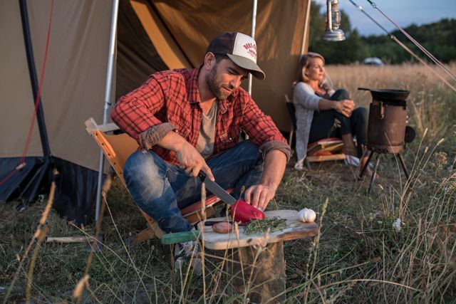 Een stel is bezig met het bereiden van eten voor hun tent tijdens hun kampeervakantie in Drenthe.