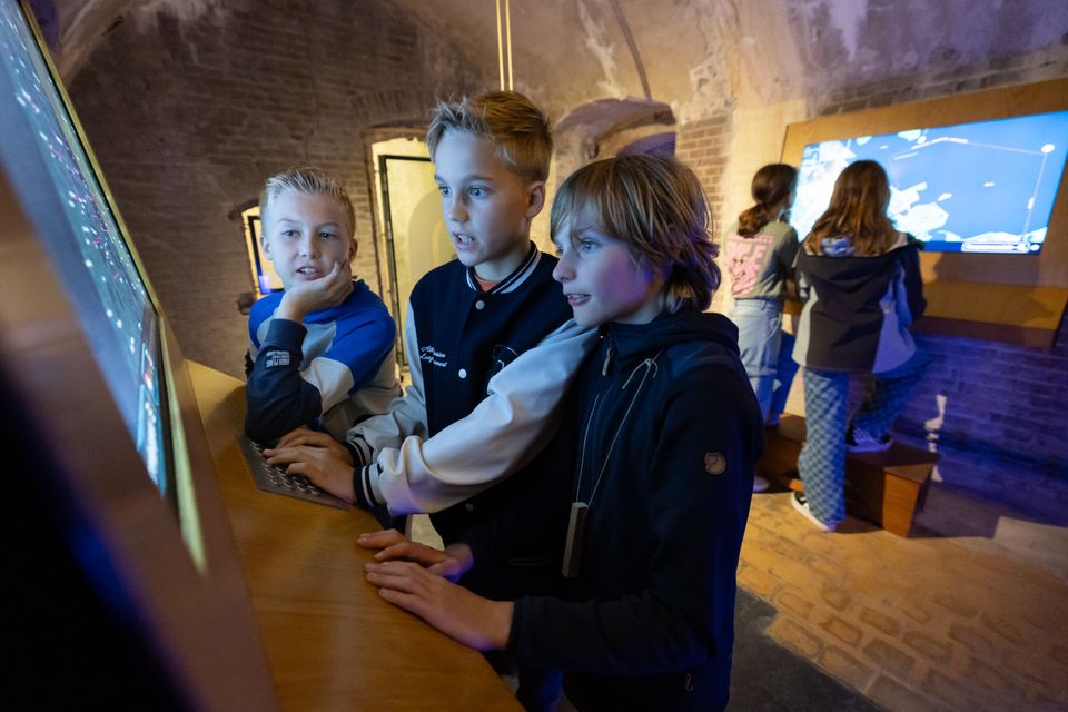 Kinderen spelen het computerspel 'Het geheime wapen' op Fort Pampus in de fortgangen.