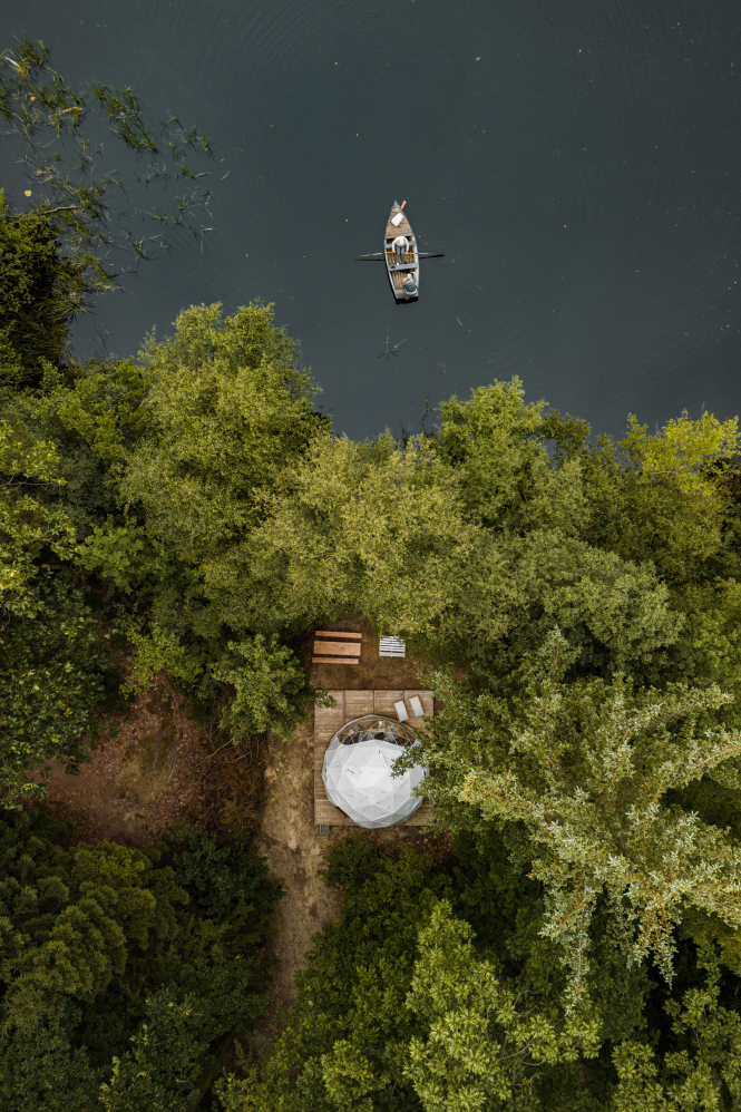 Een bootje vaart weg van de steiger, het pingomeertje op, bij de overnachtingsdome op het natuurkampeerterrein in de Drentse natuur