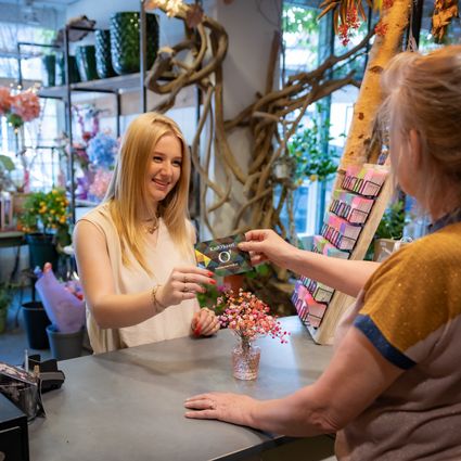 Eigenaresse bloemenzaak Belle Rose overhandigt KadO'kaart aan klant