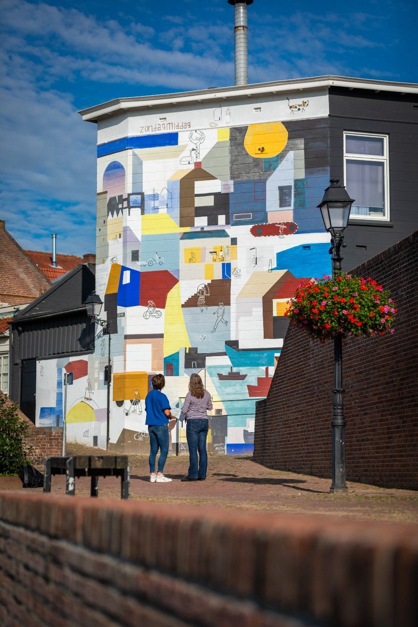 Twee personen kijken naar een muurschildering.