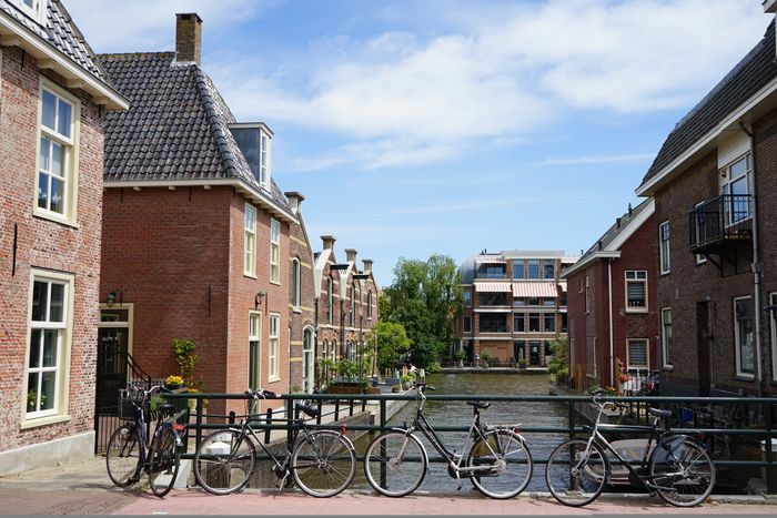 Fietsen geparkeerd op een brug in het historische centrum van Alphen aan den Rijn, met uitzicht op grachtenpanden en water onder een blauwe lucht.