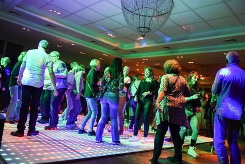 Lachende dansers op de lichtvloer tijdens het Jaren 80 Feest in De Postwagen Tolbert.