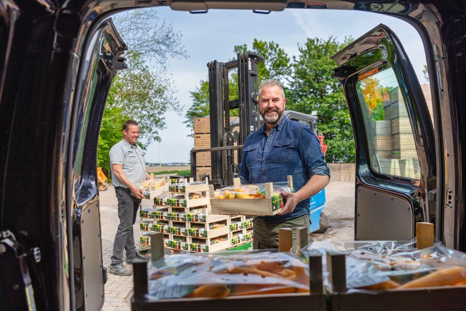 Mannen laden fruitkistjes uit in Flevoland
