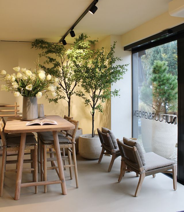 Houten tafel met stoelen, bloemen en andere accessoires bij winkel Nu Puur & Groen in Oisterwijk