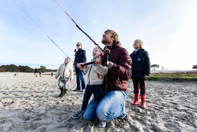 Een vader vliegert met zijn kinderen in de Soesterduinen