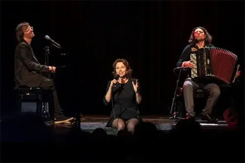Een vrouw die zingt en twee mannen op muziekinstrumenten