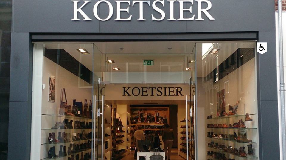 Speciaalzaak Koetsier Schoenen Woerden, provincie Utrecht, Groene Hart, winkelgevel met glazen deuren en wandpresentaties met leren schoenen en laarzen in het centrum.