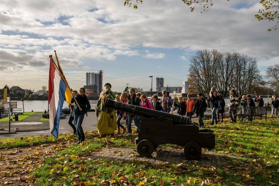 Een groep kinderen wandelen langs een oud kanon van de Hollandse Waterlinie dat gericht is op het water.