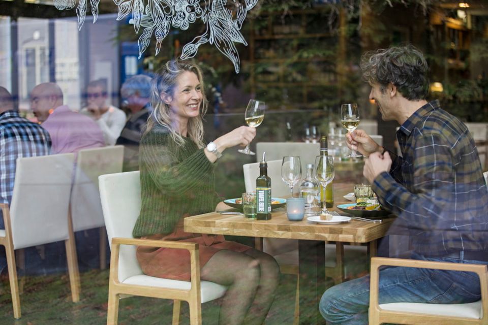 Ein Mann und eine Frau sitzen am Tisch zu Abend und stoßen mit einem Glas Wein an