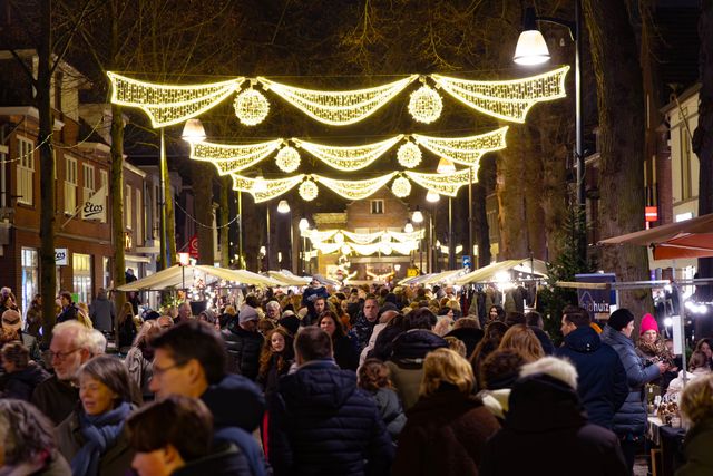 De verlichte Dorpsstraat in Oisterwijk met kramen en veel bezoekers.