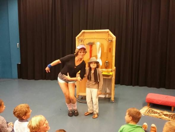 Foto van een jonge vrouw in korte broek en een meisje voor een poppenkast op een podium.