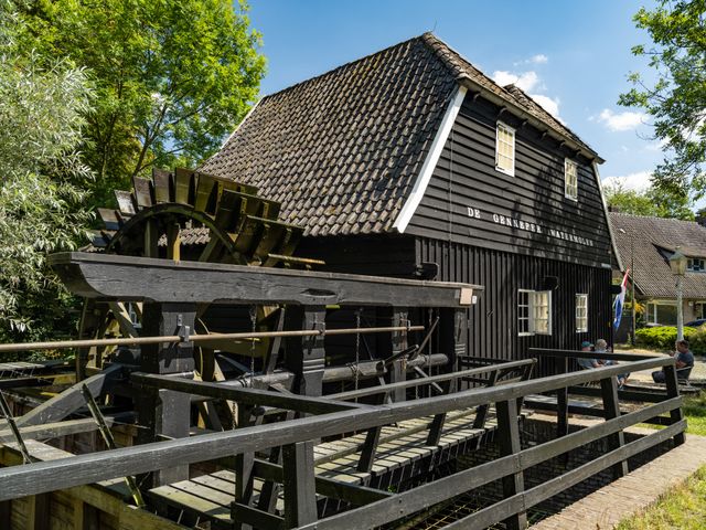 Grote zwarte houten gebouw met watermolen