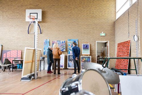 Mensen die kijken naar schilderijen in een gymzaal