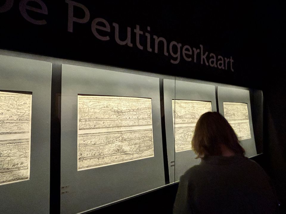 Een bezoeker bekijkt de Peutingerkaart in een donkere ruimte in het Katwijks Museum