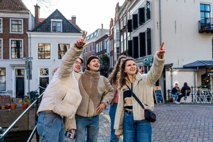 Groep vrienden ontdekt Oudewater tijdens een city escape en wijst enthousiast naar historische gebouwen in de sfeervolle binnenstad.