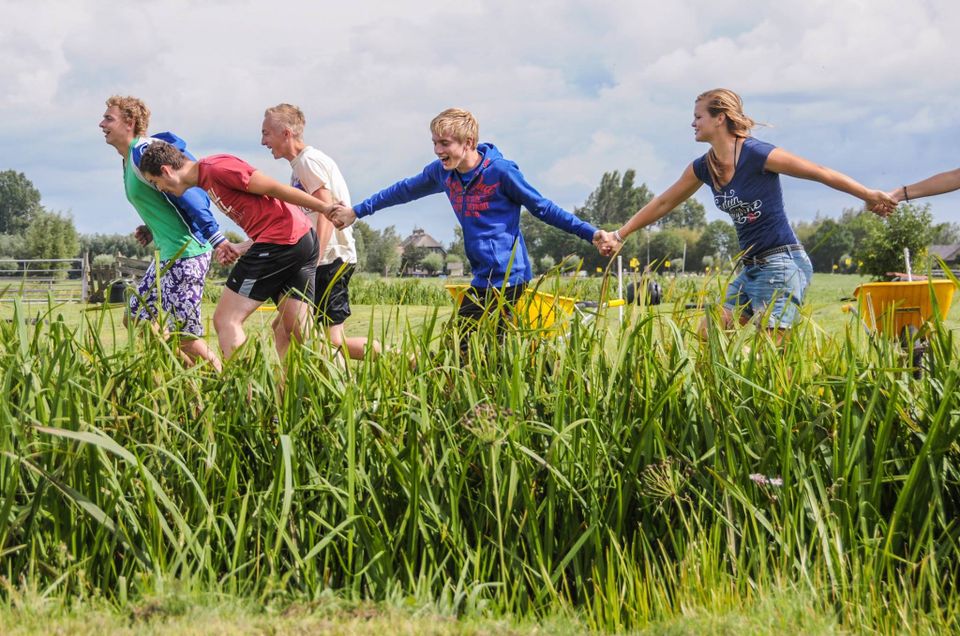 Kinderen rennen hand in hand door het weiland bij Boerderij Kamerik