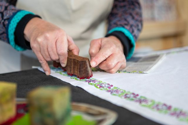 Ambachtsvrouw bedrukt met de hand een katoenen doek met houten stempel – traditioneel textielambacht in de Katoendrukkerij Amersfoort