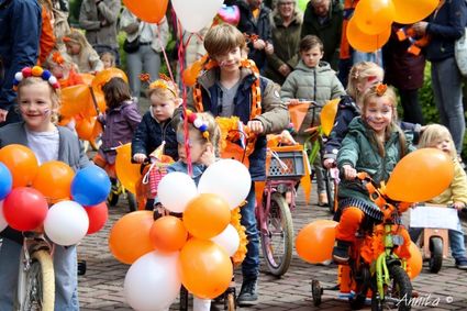 Kinderen met versierde fietsen in oranje en rood, wit en blauw kleuren