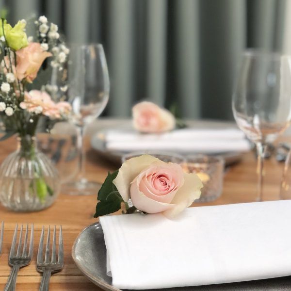 Een close-up van een gedekte tafel met een roze roos bij Lokaal 55 in Sneek.